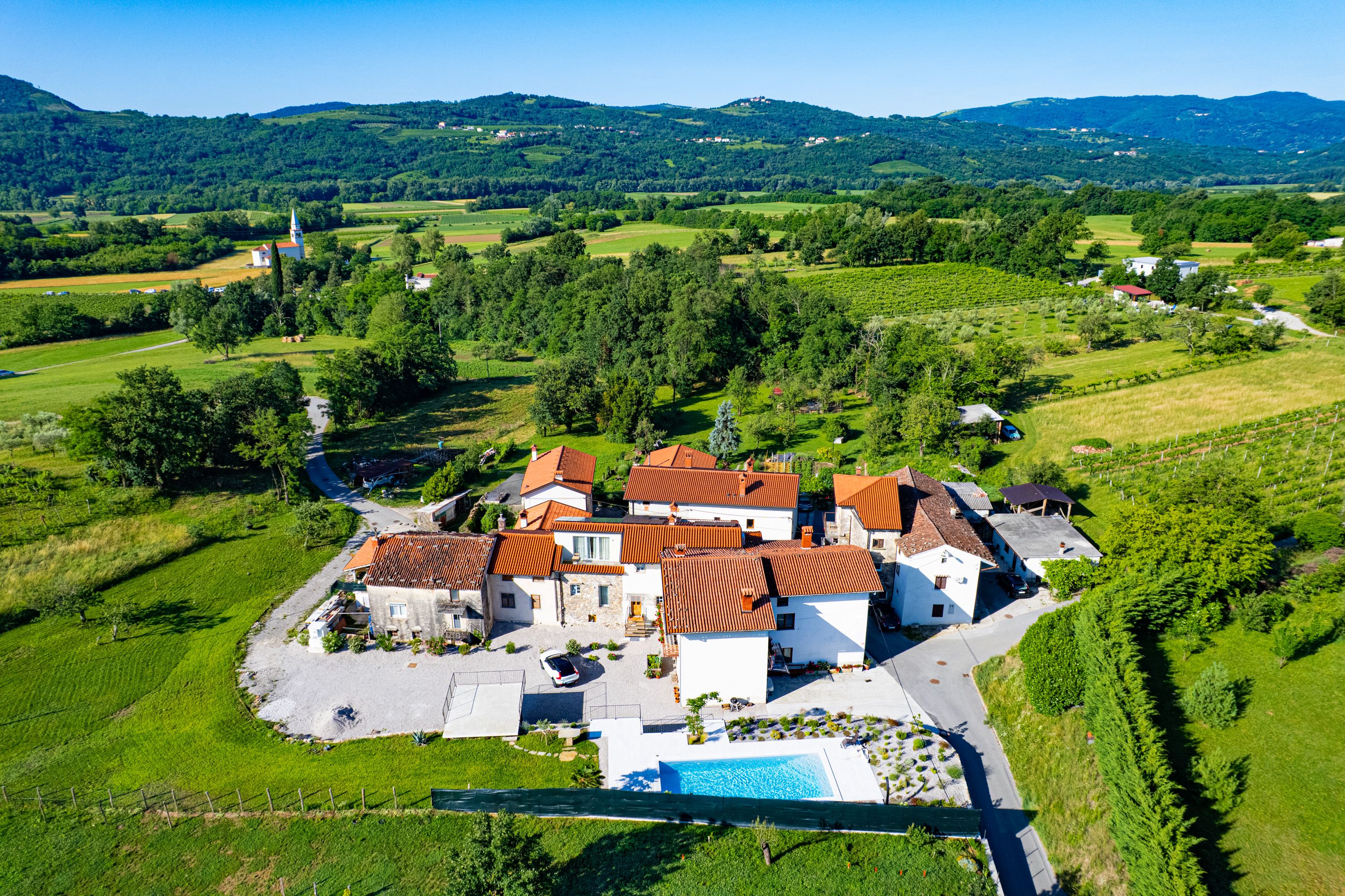 Zračni pogled na domačijo, cerkev in Vipavsko dolino