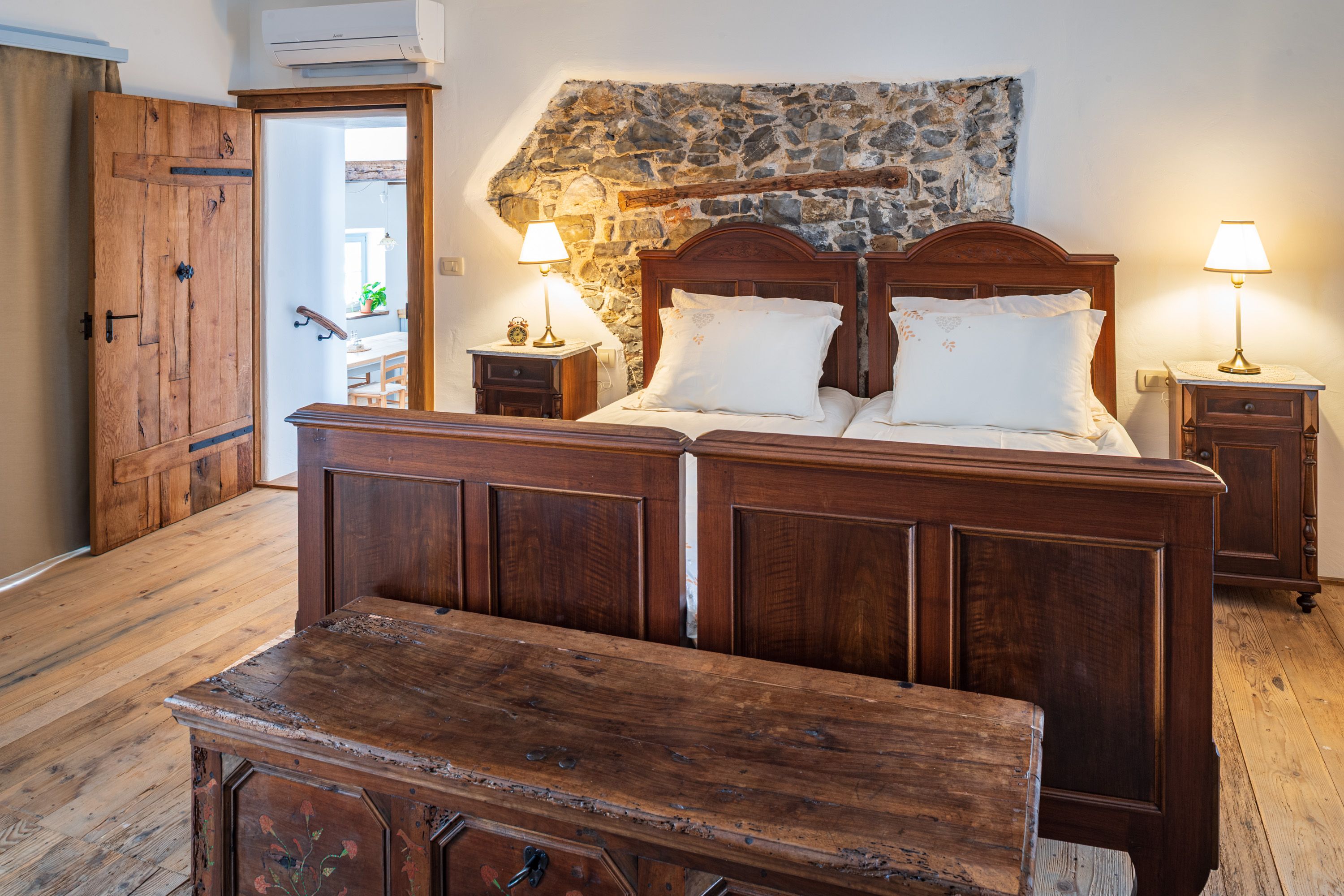 Bedroom with an antique bed by a stone wall